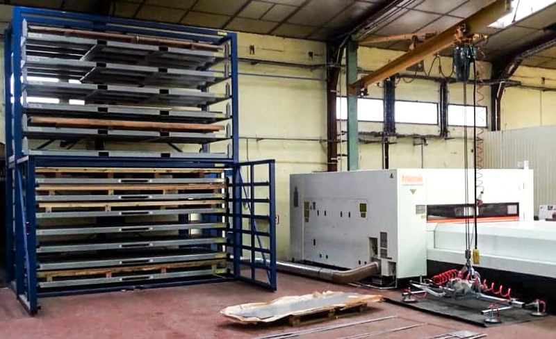 Double-stack blue sheet rack next to Mazak laser cutter and vacuum suction lifter