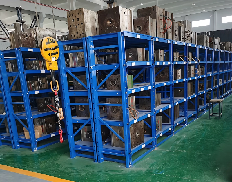 How Drawer Mould Rack Storage Helps a North American Security Hardware Toolroom Keep Changeovers Moving 6 Blue heavy-duty mold storage racks with die plates and an electric chain hoist in a factory workshop